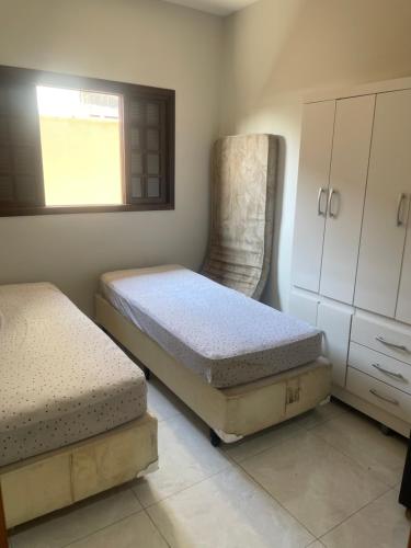 1 Schlafzimmer mit 2 Betten, einem Schrank und einem Fenster in der Unterkunft Casa de praia Itanhaém Cibratel 2 concorrida in Itanhaém