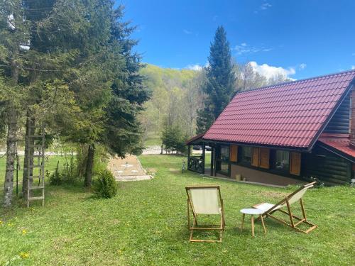 ein Haus mit einer Bank und einem Stuhl im Hof in der Unterkunft Puhova Koliba in Delnice