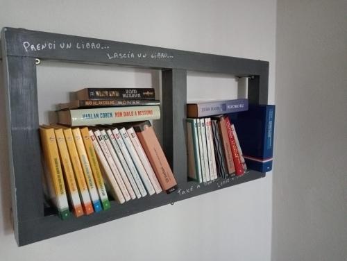 a book shelf filled with books on a wall at Casa Chiarli-Belforte Monferrato in Tagliolo Monferrato