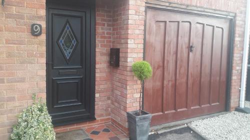 a house with a wooden door and a brick wall at No.9 in Tettenhall