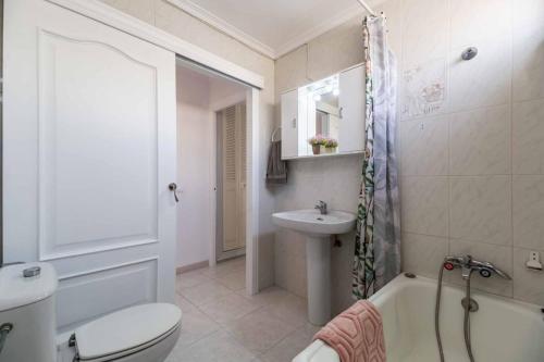 a bathroom with a toilet a sink and a bath tub at Paseo Marítimo Rey de España in Fuengirola