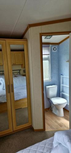 a bedroom with a bed and a bathroom with a toilet at Mollies Den in Ingoldmells