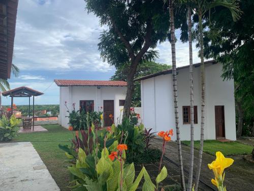 una casa blanca con flores delante en Morro Branco Suítes - Hospedaria Morro Branco, en Beberibe