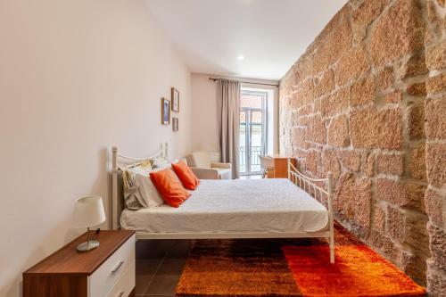 a bedroom with a bed and a brick wall at Porta 116 in Vila Real