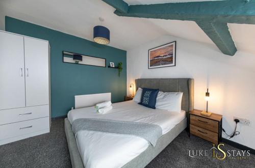 a bedroom with a bed and a blue wall at Luke Stays - Granville Street in Gateshead