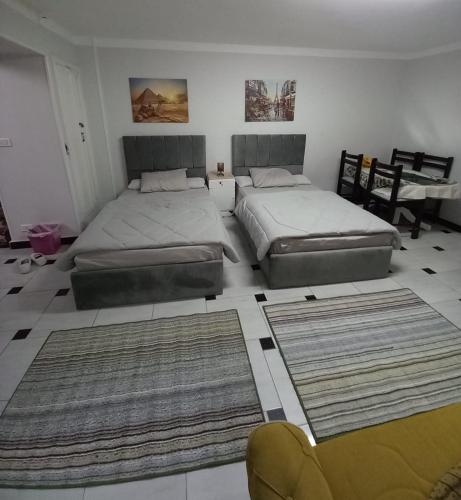 1 dormitorio con 2 camas, 2 sillas y alfombras en شاليه في المعموره en Alexandría