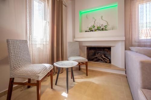a living room with two chairs and a table and a fireplace at Irida Residence in Keri