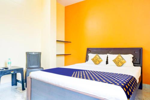 een slaapkamer met een bed met een oranje muur bij SPOT ON Hotel Shree Samarth Lodging in Kolhapur