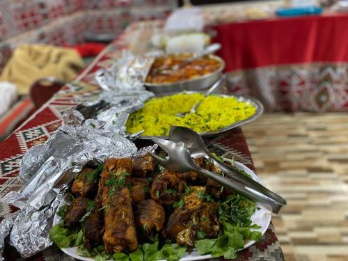 a table topped with plates of food with meat and vegetables at Wadi Rum albasli in Wadi Rum