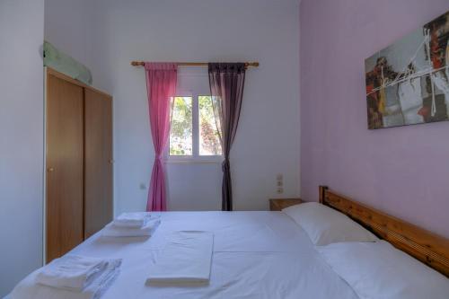 a white bed in a bedroom with a window at Korfes Apartments in Kamilari
