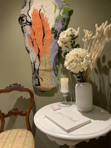 a white table with a vase of flowers and a vase of flowers at Bärsta Svit BnB in Kolbäck