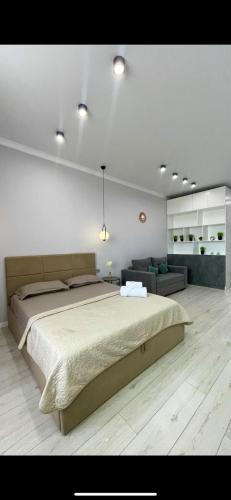 een slaapkamer met een groot bed en een bank bij Квартира in Pavlodar