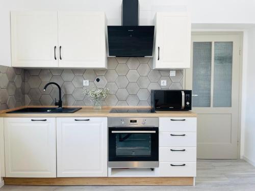 uma cozinha com armários brancos, um lavatório e um micro-ondas em Apartma Srečko, Sežana em Sežana