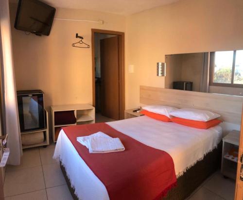 a bedroom with a large bed with red and white pillows at Pousada Krolow in Pelotas