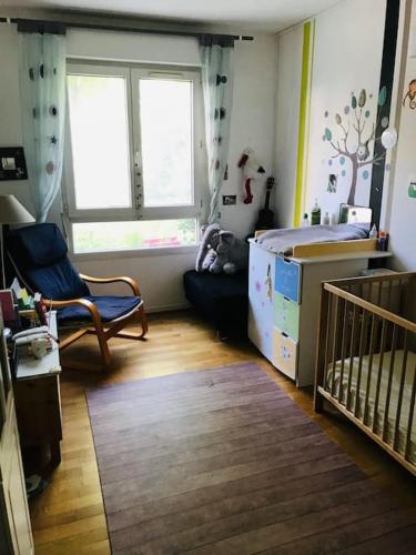 - une petite chambre avec un lit bébé et une chaise haute dans l'établissement Appartement jardin privatif, à Asnières-sur-Seine