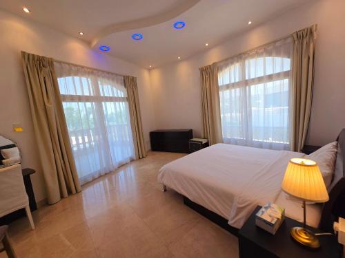 a bedroom with a bed and two large windows at Stay Room Jumeriah Dubai in Dubai