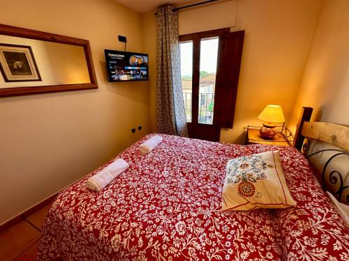 a bedroom with a bed with a red bedspread and a window at Posada La Fragua in Gandullas