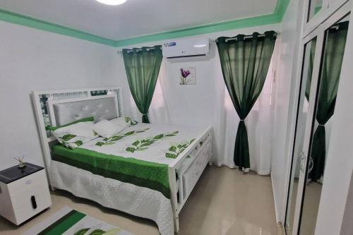 Cette petite chambre comprend un lit avec des draps verts et blancs. dans l'établissement Lujosa y espaciosa Villa María., à Santiago de los Caballeros