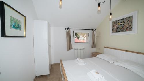 a white bedroom with a white bed and a mirror at Vida`s house in Virpazar