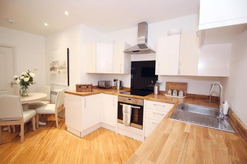 a kitchen with white cabinets and a sink and a table at Yarm Luxury Apartments - Bank House - private gated carpark in Stockton-on-Tees