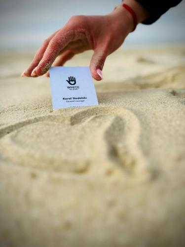 a person reaching for a piece of paper in the sand at Willa Aleksandra White Glove in Władysławowo