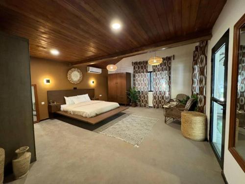 a bedroom with a bed and a chair in a room at Maison-Villa de charme à Cotonou in Cotonou