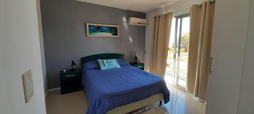 Un pequeño dormitorio con una cama azul y una ventana en YellowStone, en Balneario Buenos Aires