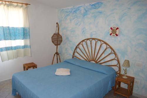 1 dormitorio con 1 cama con pared azul en Borgo del Tennis - Sa Ventana 2, en Badesi
