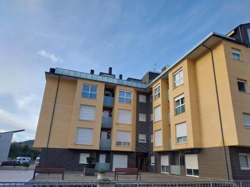 un edificio de apartamentos con bancos delante en Apartamento en Unquera, en Unquera