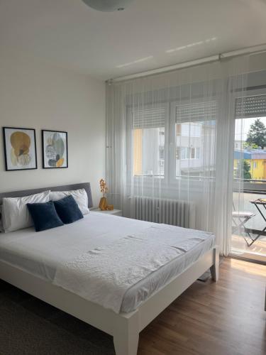 a white bedroom with a large bed and a window at Danube Sunrise in Kladovo
