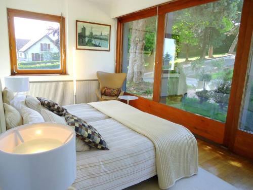 ein Schlafzimmer mit einem großen Bett und einem Fenster in der Unterkunft Villa with Lake Geneva views; 1960 (mid century modern) style in Neuvecelle