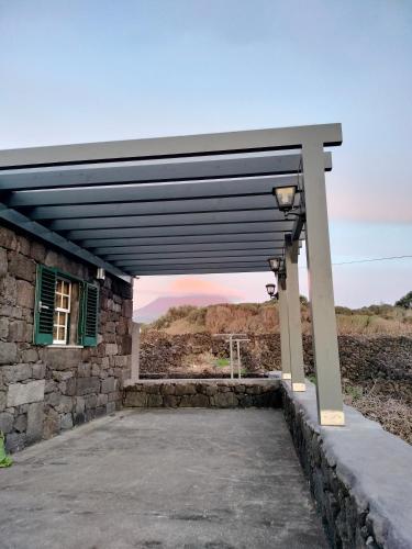 awning over a stone building with the sunset in the background at A Casa da Formosinha in Madalena