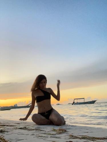 a woman in a bikini sitting on the beach at Hotel Costa Linda Beach Boca Chica in Boca Chica