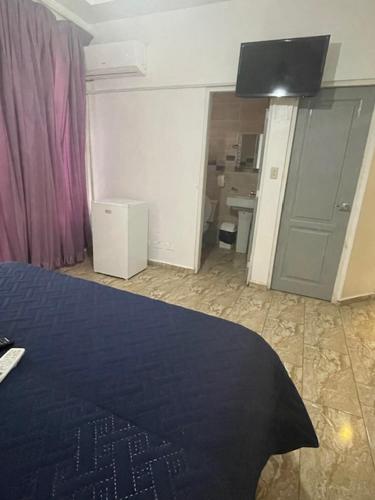 a bedroom with a blue bed and a bathroom at Hotel Costa Linda Beach Boca Chica in Boca Chica