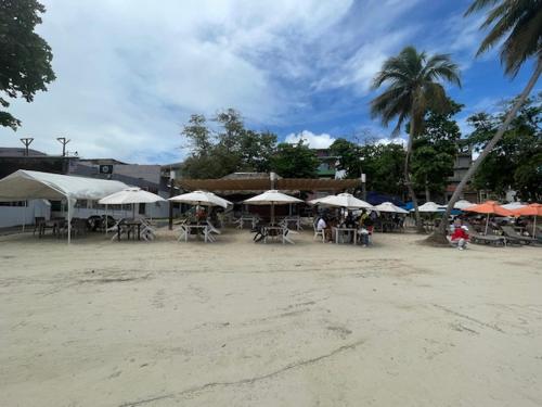 a group of tables and chairs with umbrellas on a beach at Hotel Costa Linda Beach Boca Chica in Boca Chica