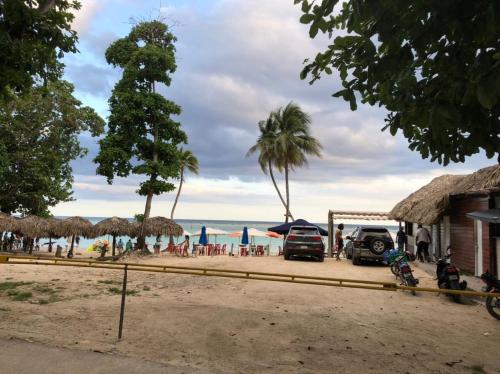 a beach with umbrellas and people and the ocean at Hotel Costa Linda Beach Boca Chica in Boca Chica
