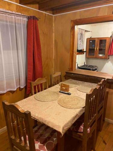 a dining room with a table with chairs and a kitchen at Arriendo casa en NELTUME a minutos de huilo-huilo in Neltume