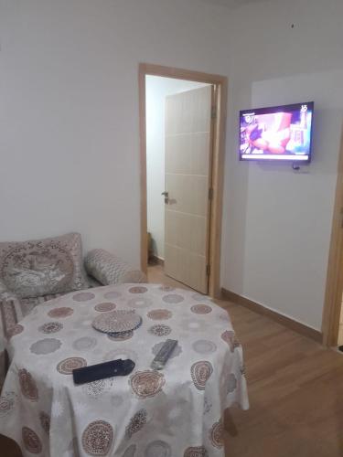 Zimmer mit einem Tisch und einem TV an der Wand in der Unterkunft New Rif Appartement Appelle moi 07 et 74 et 41 et 16 et 91 in Al Hoceïma