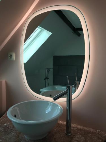 ein Bad mit einem runden Spiegel und einem Waschbecken in der Unterkunft Gite Saint Georges in Comines