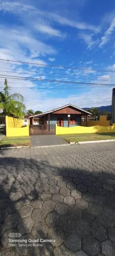 a house with a yellow building in front of a street at Casa com Piscina na Morada da Praia in Bertioga