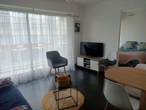 un salon avec une télévision, une table et des chaises dans l'établissement Le Toutapieds, à Le Touquet-Paris-Plage