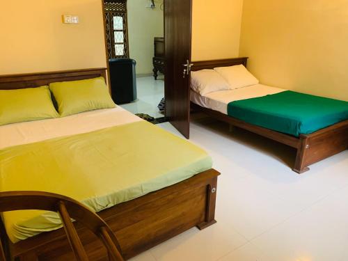 a bedroom with two beds and a chair in it at Four Seasons Villa in Anuradhapura