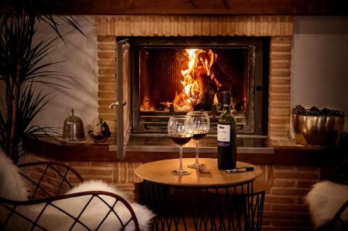 a table with two glasses of wine in front of a fireplace at Hotel Rural Flor de Almendro in Loarre