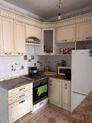 eine Küche mit weißen Schränken und einem weißen Kühlschrank in der Unterkunft Квартира in Zaozërnyy