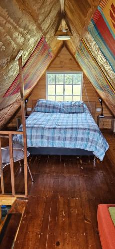 Cama en habitación de madera con ventana en Cabaña el rincon de la abuela en Guasca