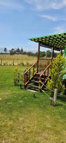 a wooden deck with a gazebo in a field at Cabaña el rincon de la abuela in Guasca