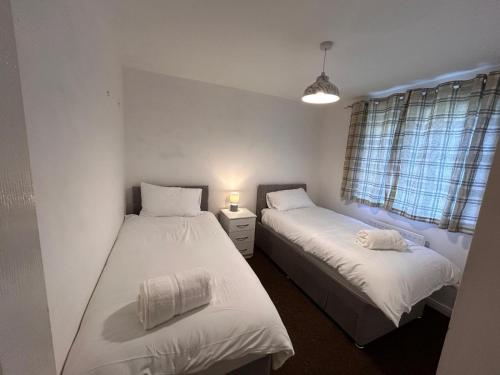 two beds in a room with white sheets at Vyna Place-Close to City Hospital in Nottingham