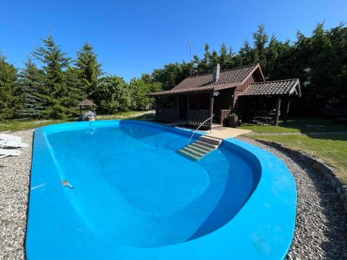 a large blue swimming pool in front of a house at Agroturystyka w Łęgowie, Domki na Mazurach in Olecko