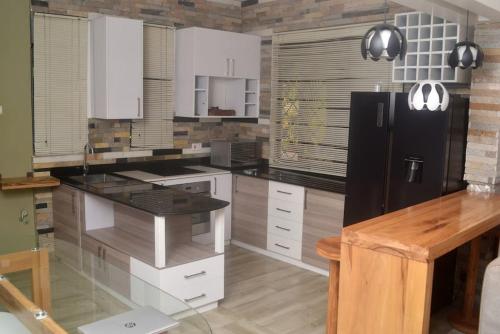 a kitchen with white cabinets and a black refrigerator at Isabirye residence in Kampala