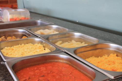 a row of metal containers of food on a counter at Hotel Praia dos Carneiros in Tamandaré